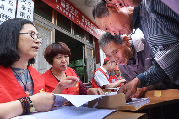 圖為國際檔案日宣傳活動現場義烏市檔案局工作人員幫助西田村村民查閱1951年土地證并提供查檔咨詢服務（
